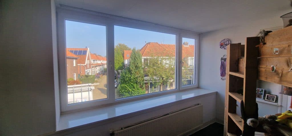 Vrijstaande raamkozijnen met uitzicht op een rustige straat met huisjes en bomen, onderhouden door Glaszetter Friesland.