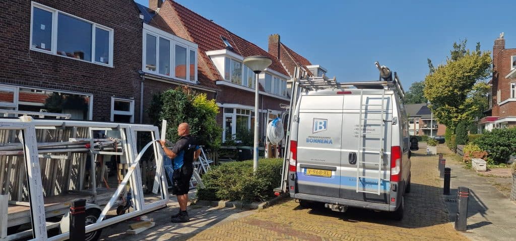 Vakkundige glashandel en glasservice medewerker bij het installeren van ramen en glaswerken voor een woning in Friesland op een zonnige dag.