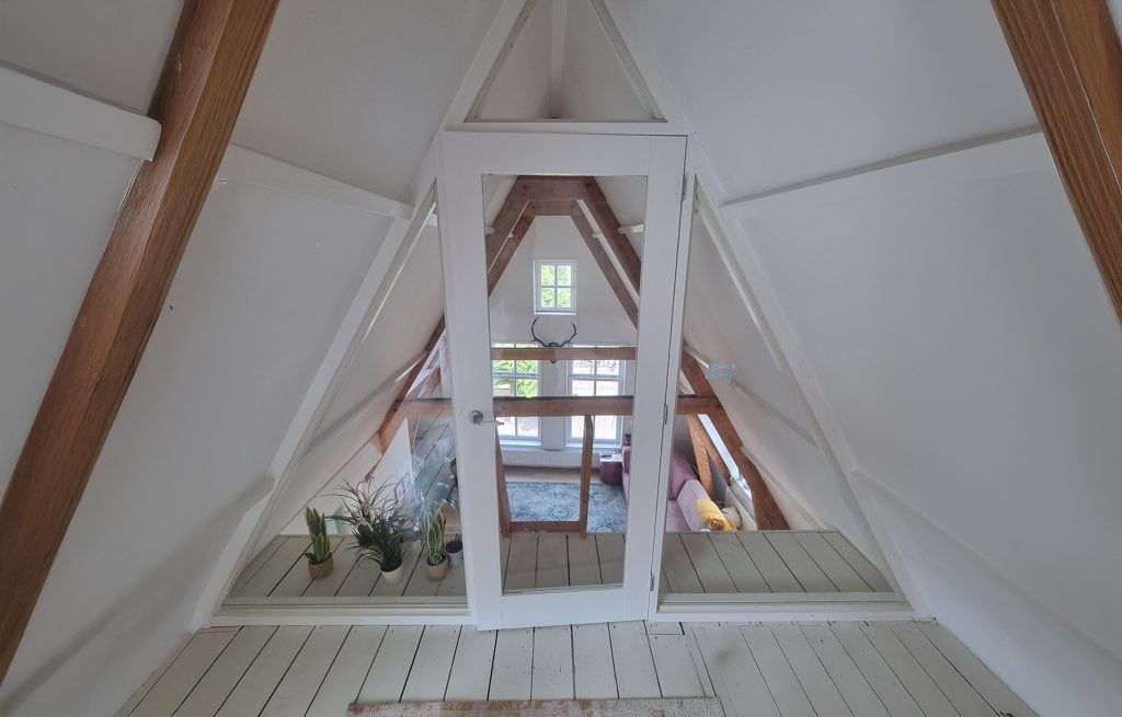 Hoogwaardige glazen pui met witte houten kozijnen, perfect voor het verbeteren van het natuurlijke licht in de slaapruimte en het creëren van een open, frisse sfeer.